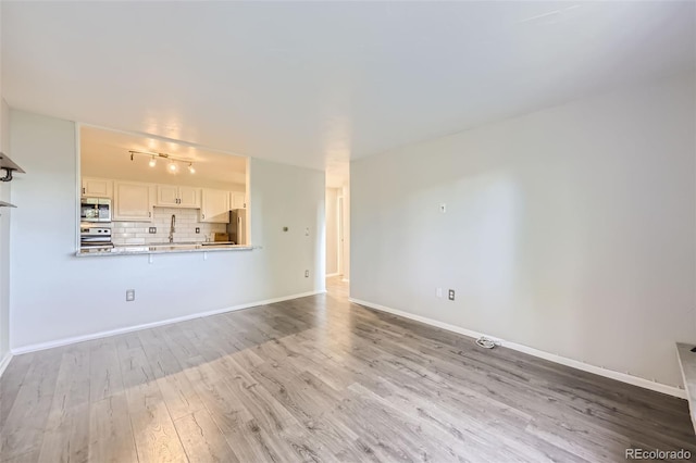 1008 N Corona St Unit 403, Denver, CO 80218 - unfurnished living room featuring wood finished floors, rail lighting, and baseboards