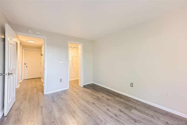 1008 N Corona St Unit 403, Denver, CO 80218 - unfurnished bedroom featuring light wood-style floors, baseboards, a closet, and a walk in closet