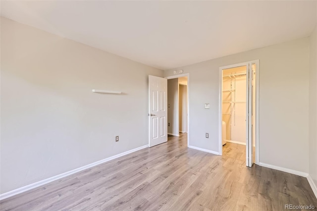 1008 N Corona St Unit 403, Denver, CO 80218 - unfurnished bedroom with wood finished floors, baseboards, a walk in closet, and a closet