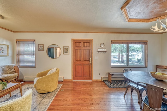 interior space featuring a textured ceiling, a baseboard heating unit, light wood finished floors, and ornamental molding