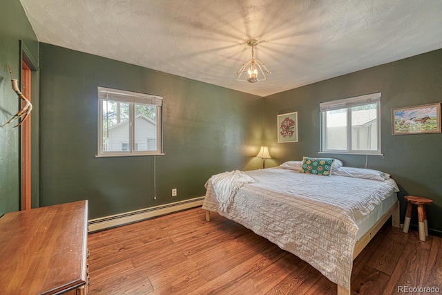bedroom featuring a baseboard radiator, wood finished floors, and baseboards