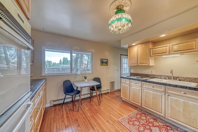 kitchen featuring a baseboard radiator, light wood-style floors, light brown cabinets, and a sink