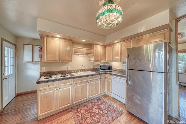 kitchen with light brown cabinetry, light wood finished floors, a sink, and stainless steel appliances
