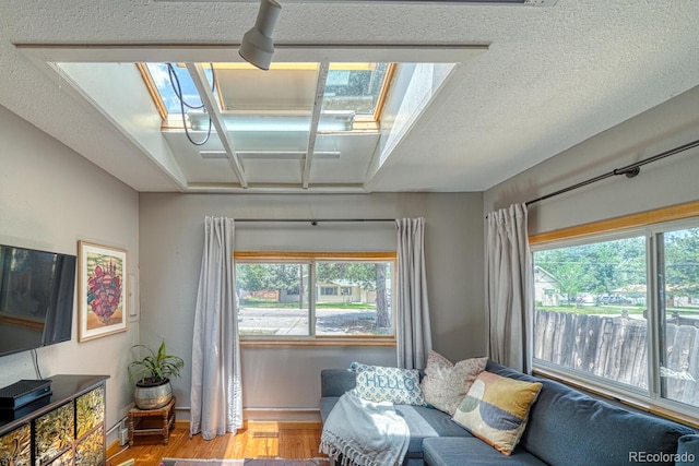 living area with a wealth of natural light, wood finished floors, and baseboards