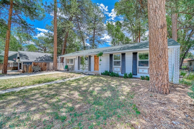 ranch-style home featuring roof with shingles, a front yard, and fence