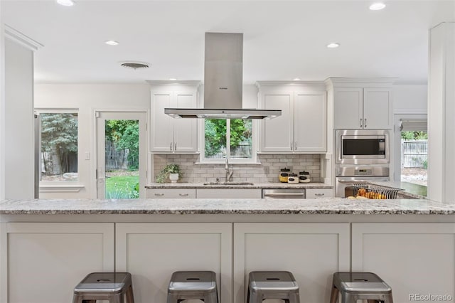 3190 S Detroit St, Denver, CO 80210 - kitchen with island range hood, appliances with stainless steel finishes, white cabinets, plenty of natural light, and recessed lighting