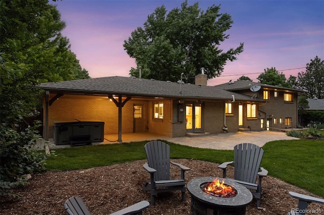 3190 S Detroit St, Denver, CO 80210 - rear view of house with a hot tub, a fire pit, a patio area, a lawn, and brick siding