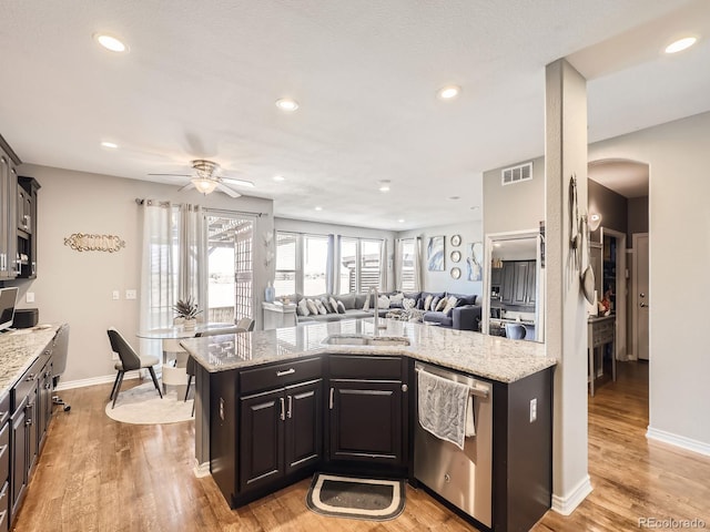 kitchen featuring stainless steel dishwasher, light wood-style flooring, visible vents, and a sink