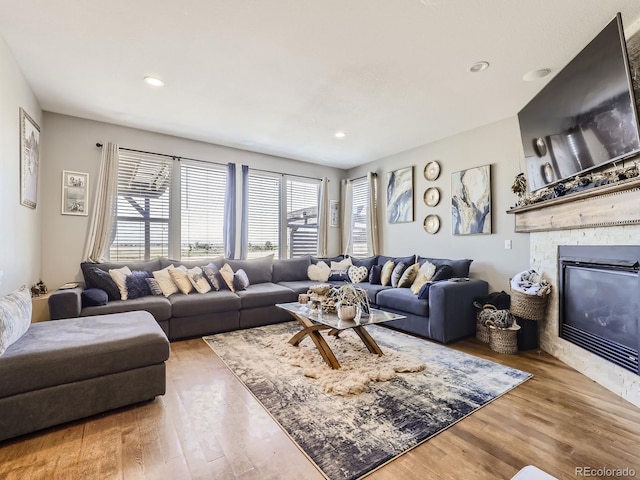 living area with a glass covered fireplace, wood finished floors, and recessed lighting