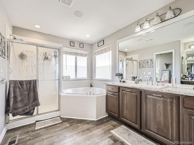 bathroom with visible vents, a garden tub, a stall shower, wood finished floors, and vanity