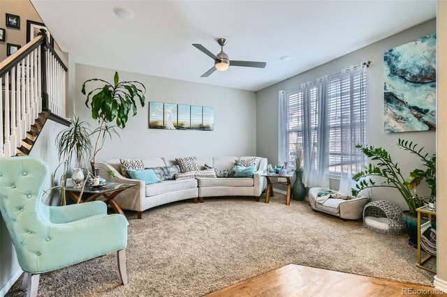 living area with a ceiling fan, stairs, and carpet