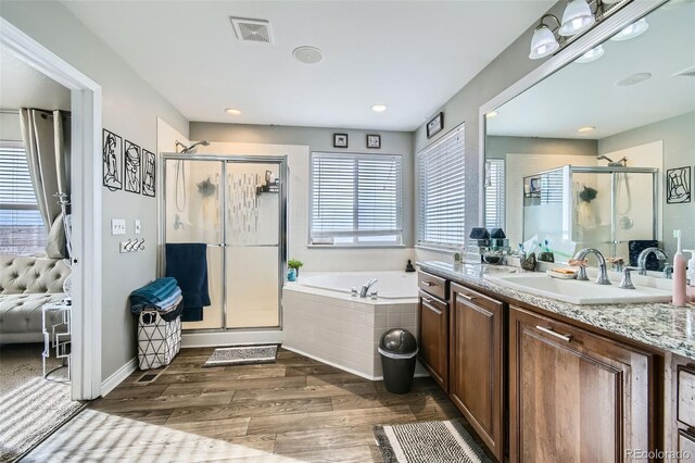 bathroom with visible vents, a garden tub, wood finished floors, a shower stall, and vanity