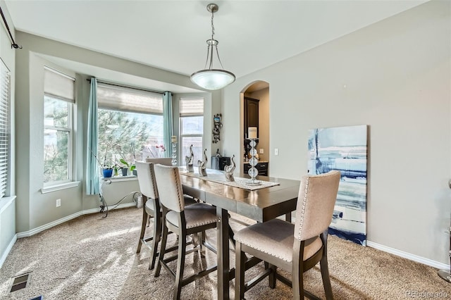 dining room with visible vents, arched walkways, light colored carpet, and baseboards