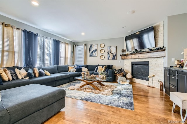 living area featuring a stone fireplace, recessed lighting, and wood finished floors