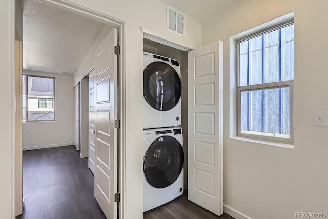 clothes washing area featuring dark hardwood / wood-style flooring and stacked washer and clothes dryer