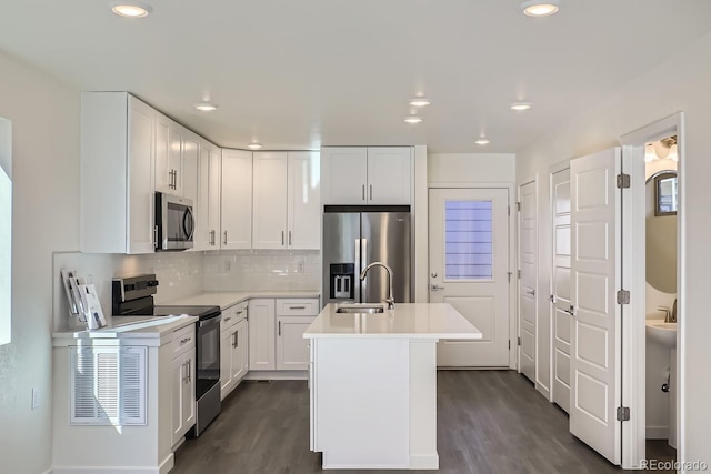 kitchen featuring a kitchen island with sink, stainless steel appliances, sink, white cabinets, and dark hardwood / wood-style floors