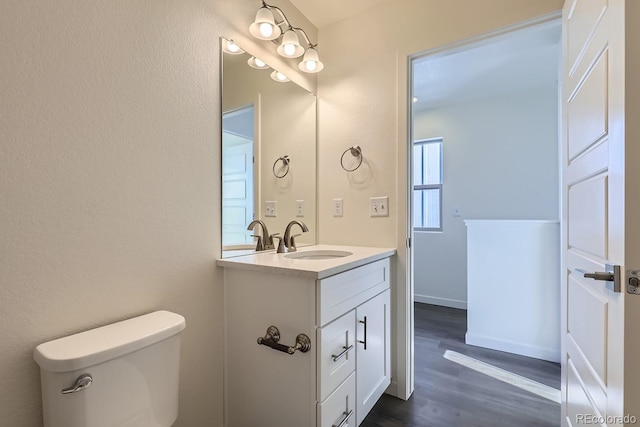 bathroom with vanity, toilet, and hardwood / wood-style floors