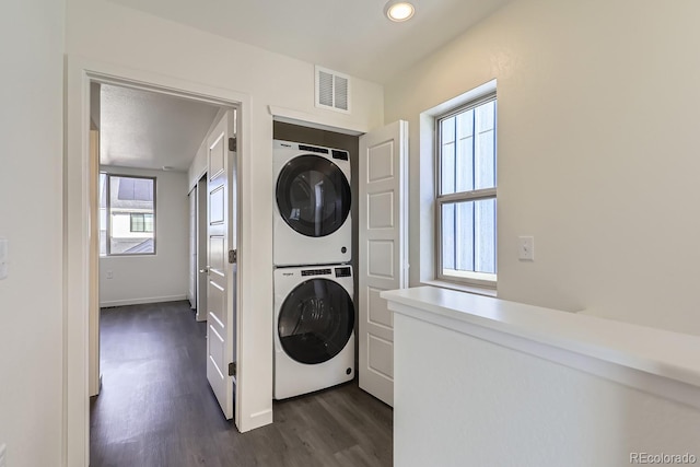 clothes washing area featuring stacked washer and dryer and dark hardwood / wood-style flooring