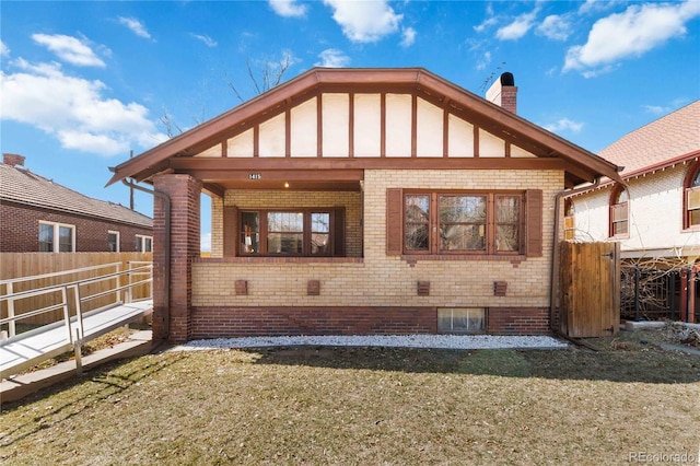 back of house featuring a lawn, fence, brick siding, and a chimney