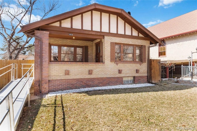 rear view of house with brick siding, a lawn, and fence