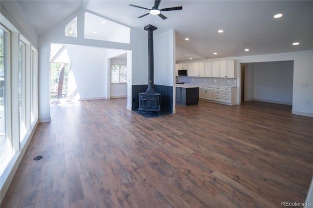 14546 Pine View Rd, Larkspur, CO 80118 - unfurnished living room featuring a wood stove, vaulted ceiling, baseboards, dark wood-style flooring, and ceiling fan