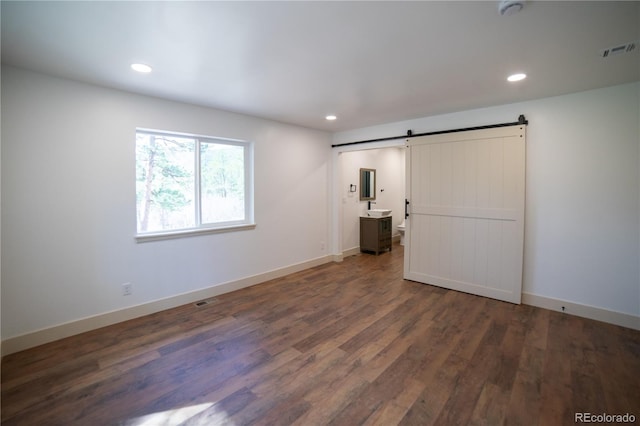 14546 Pine View Rd, Larkspur, CO 80118 - unfurnished bedroom with a barn door, wood finished floors, recessed lighting, baseboards, and ensuite bath