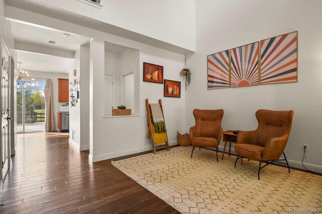 sitting room featuring dark wood-type flooring and a chandelier