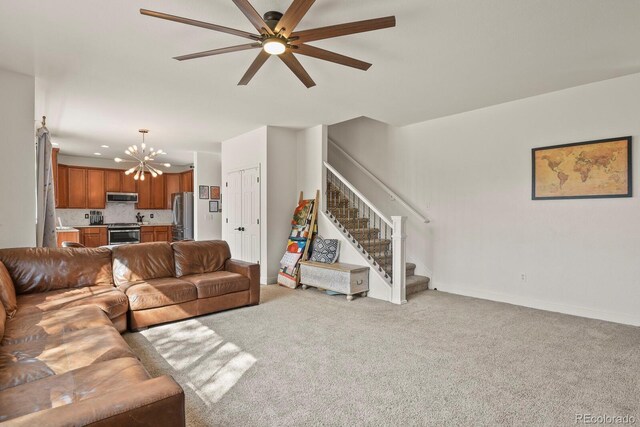 carpeted living room with ceiling fan with notable chandelier