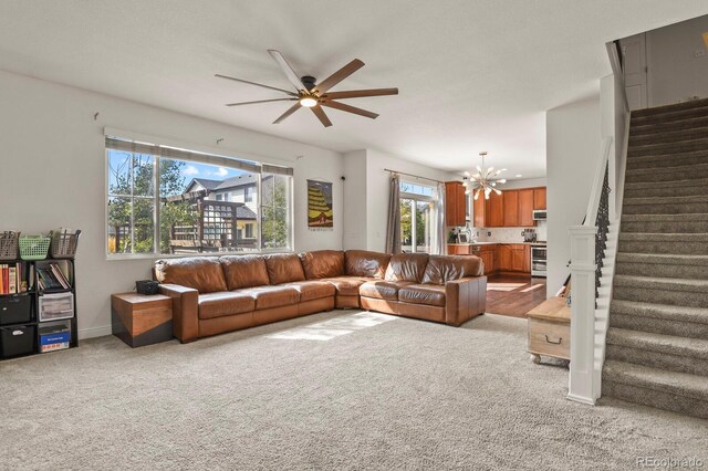 carpeted living room featuring ceiling fan with notable chandelier