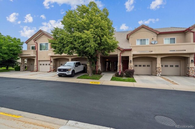 10725 Eliot Cir Unit 102, Denver, CO 80234 - view of property with stucco siding, stone siding, a garage, and driveway