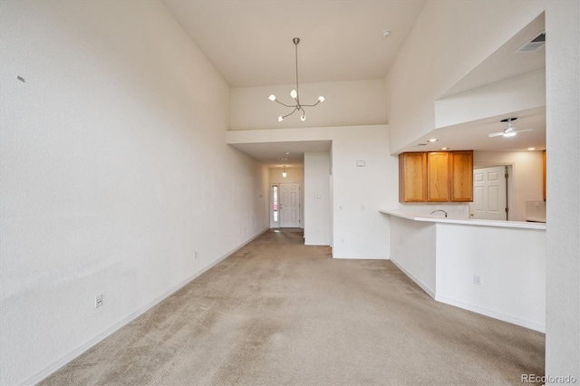 10725 Eliot Cir Unit 102, Denver, CO 80234 - unfurnished living room featuring light colored carpet, a chandelier, baseboards, ceiling fan, and a towering ceiling