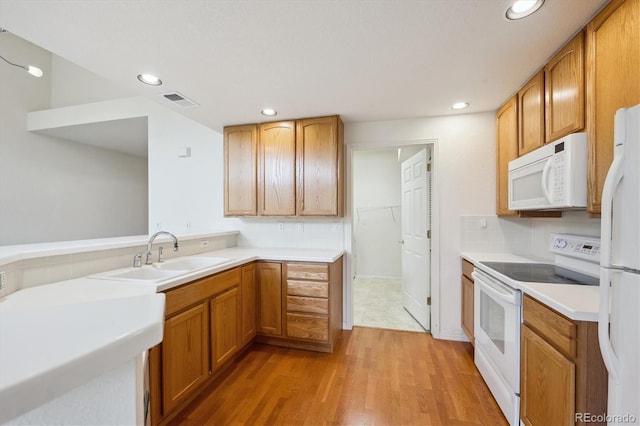 10725 Eliot Cir Unit 102, Denver, CO 80234 - kitchen featuring white appliances, a sink, recessed lighting, light wood-style floors, and light countertops