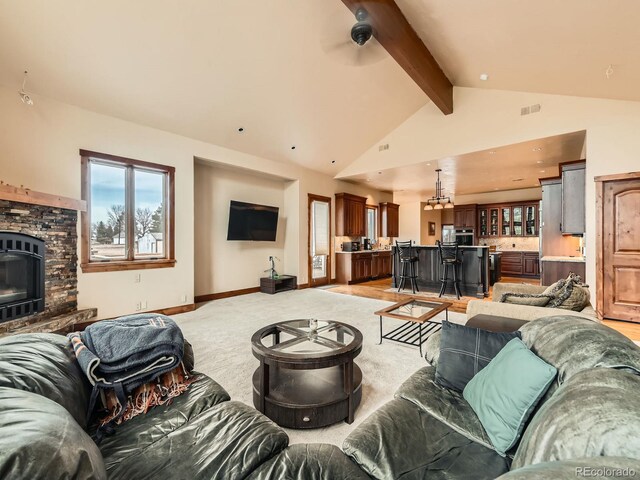 living area featuring an inviting chandelier, a fireplace, visible vents, beamed ceiling, and light colored carpet
