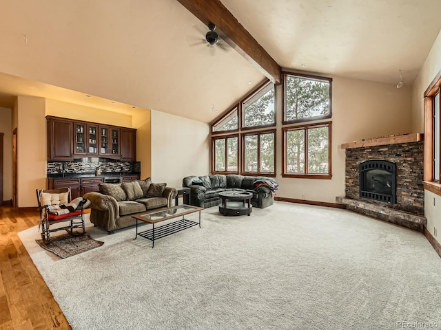 living room with baseboards, a fireplace, beam ceiling, ceiling fan, and high vaulted ceiling