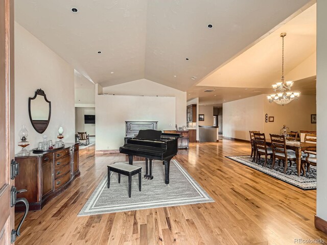 living area with a chandelier, light wood-style floors, and lofted ceiling