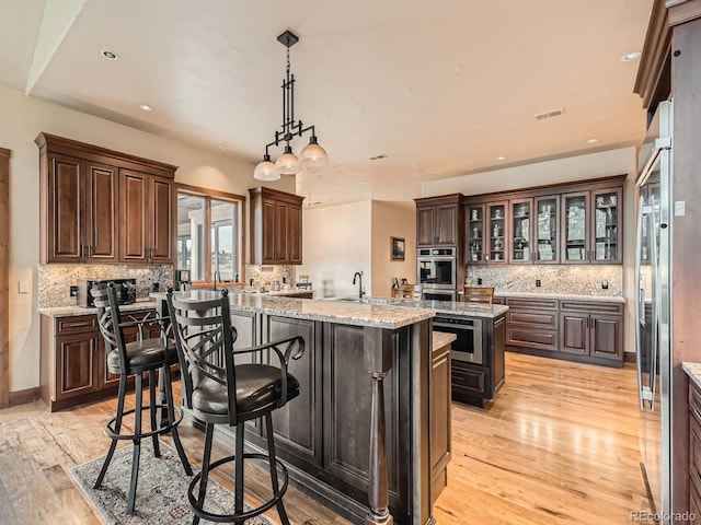 kitchen with light wood-style flooring, a center island, backsplash, and visible vents