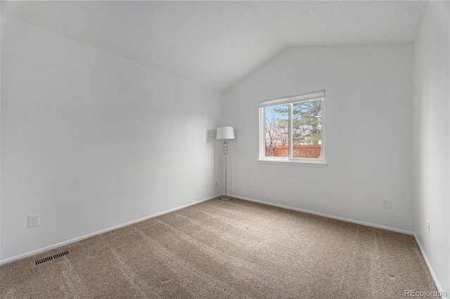 spare room with baseboards, visible vents, vaulted ceiling, a textured ceiling, and carpet floors