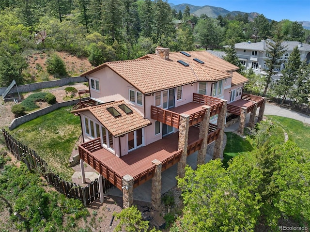 4 Pine Rd, Colorado Springs, CO 80906 - back of house with a chimney, a tiled roof, stucco siding, a deck with mountain view, and stone siding