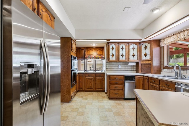 4 Pine Rd, Colorado Springs, CO 80906 - kitchen with stainless steel appliances, brown cabinetry, a sink, decorative backsplash, and light countertops