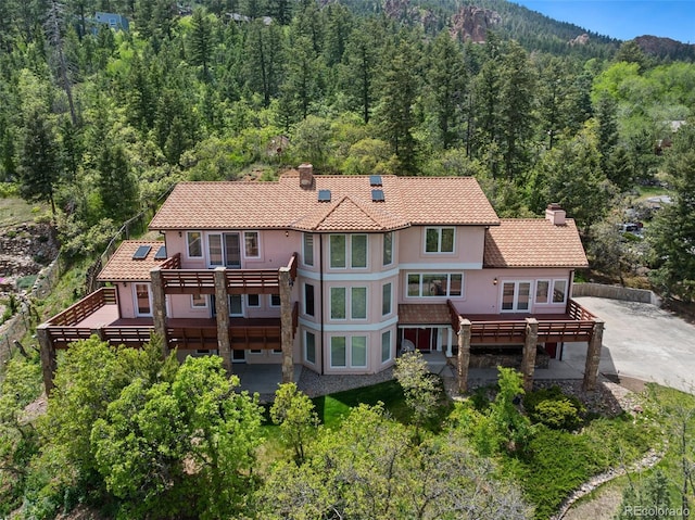 4 Pine Rd, Colorado Springs, CO 80906 - back of house featuring a chimney, a view of trees, stucco siding, and a patio