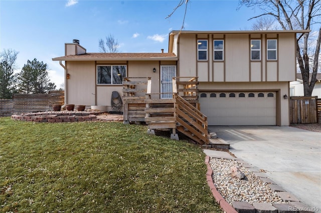 tri-level home with a chimney, concrete driveway, fence, a garage, and a front lawn