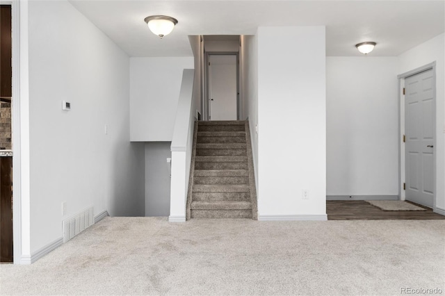 stairs with carpet flooring, visible vents, and baseboards