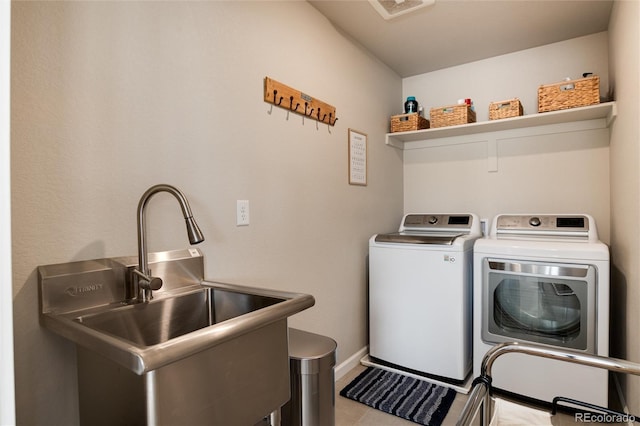 clothes washing area with washing machine and dryer, light tile patterned floors, and sink