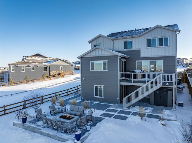 snow covered house featuring a wooden deck and an outdoor fire pit