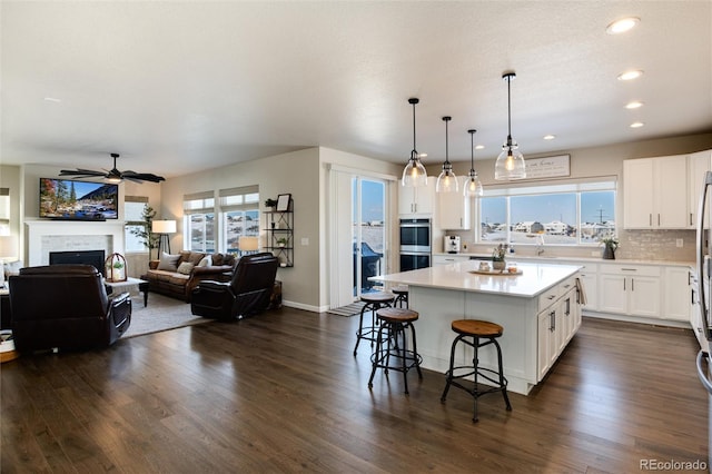 kitchen featuring double oven, white cabinetry, a kitchen bar, and a center island