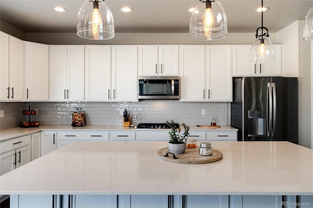 kitchen featuring appliances with stainless steel finishes, backsplash, white cabinets, and a kitchen island