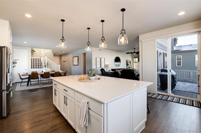 kitchen featuring decorative light fixtures, stainless steel refrigerator, white cabinetry, and a kitchen island