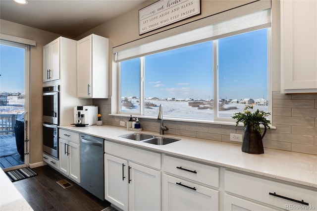 kitchen featuring decorative backsplash, sink, dark wood-type flooring, stainless steel appliances, and white cabinets