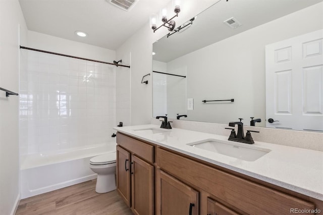 full bathroom featuring vanity, toilet, wood-type flooring, and tiled shower / bath