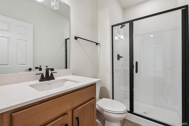 bathroom with vanity, toilet, a shower with shower door, and wood-type flooring